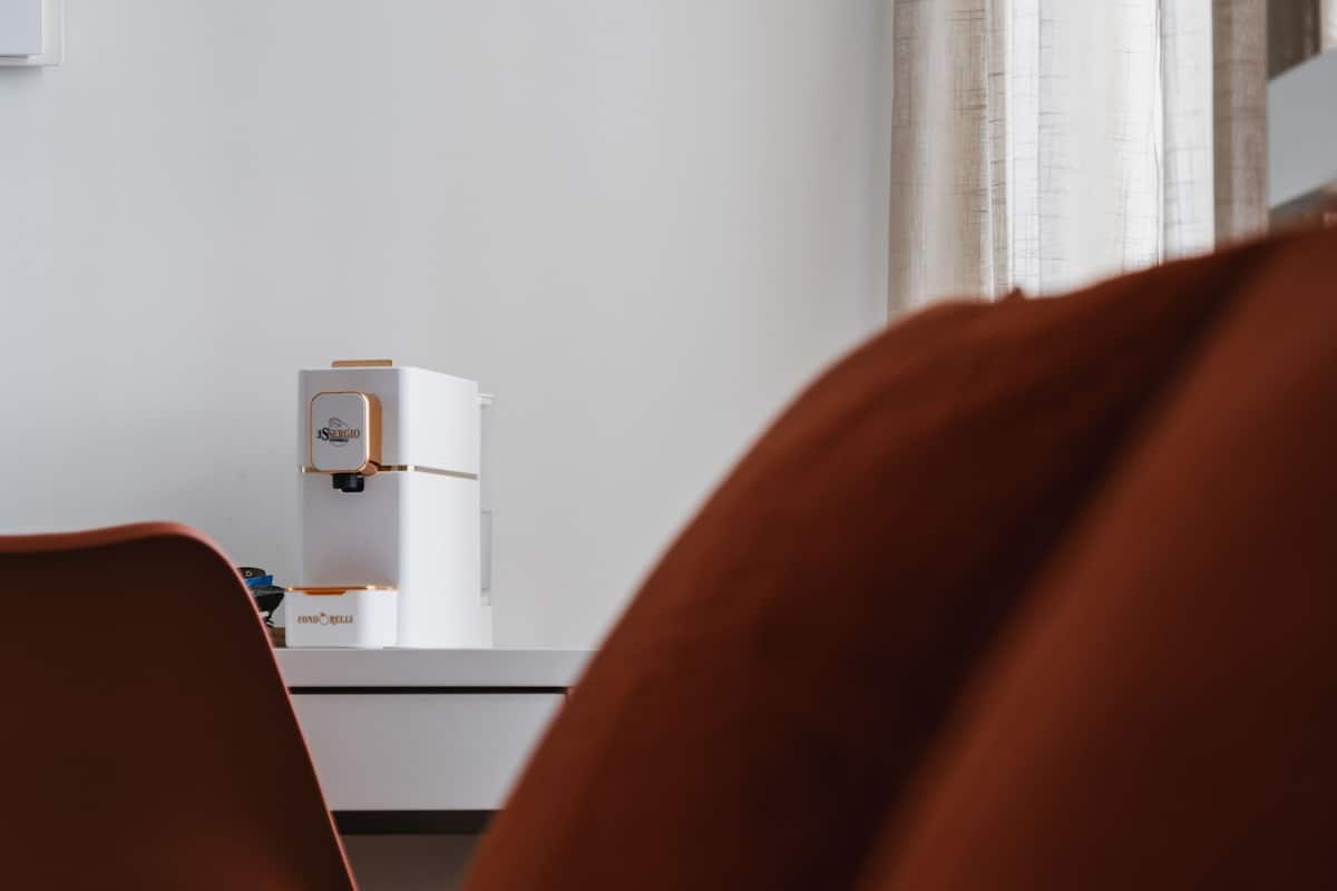 Une chambre d’hôtel avec un lit, un bureau doté d’une machine à café et une fenêtre avec des rideaux.