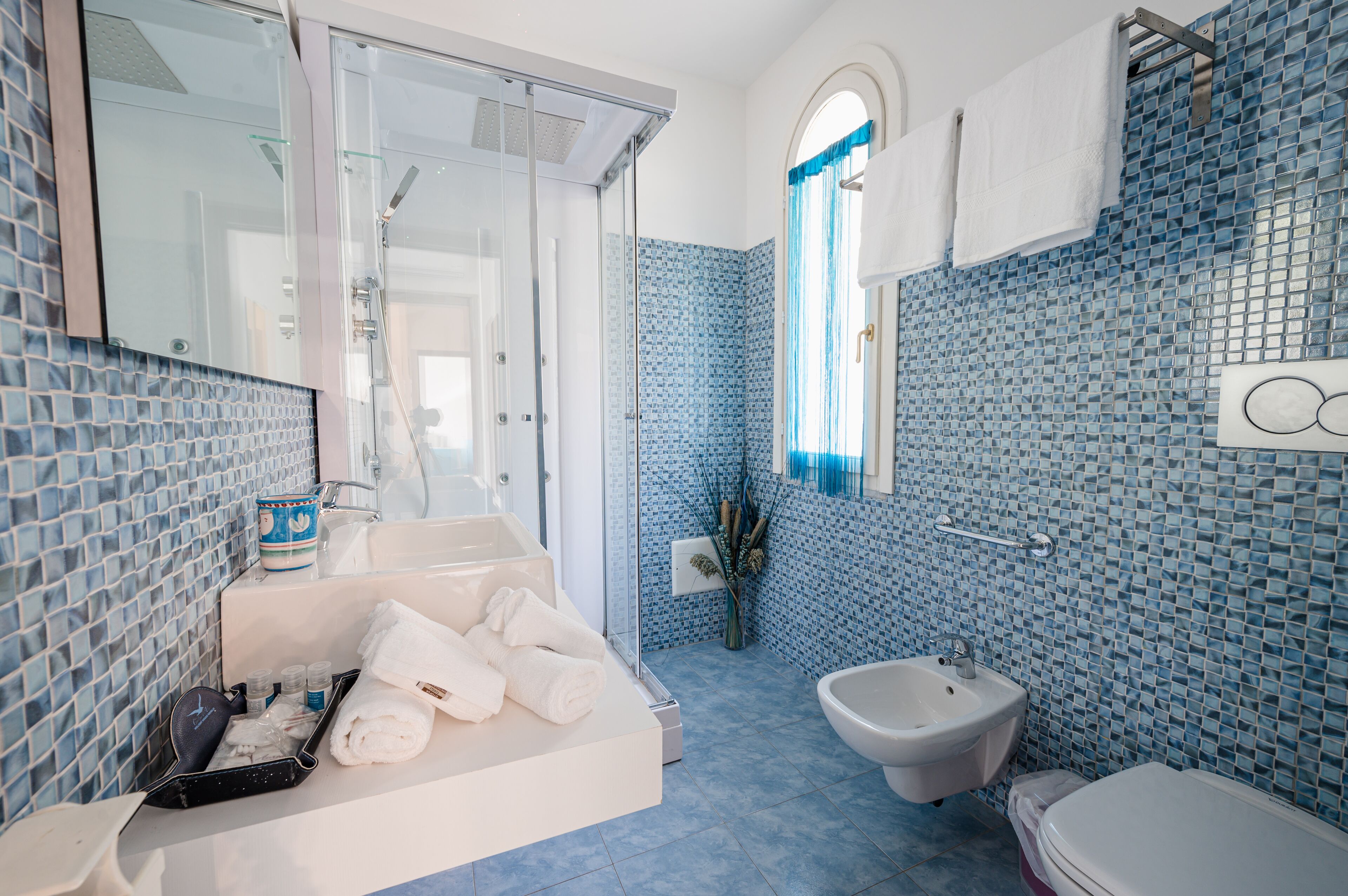 Een moderne badkamer met een glazen douche, een bidet en een bad.