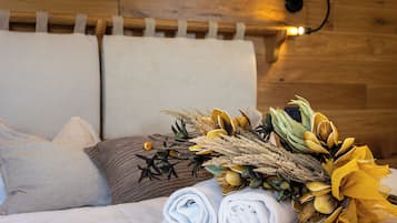 A neatly made bed with rolled towels and a decorative floral arrangement.