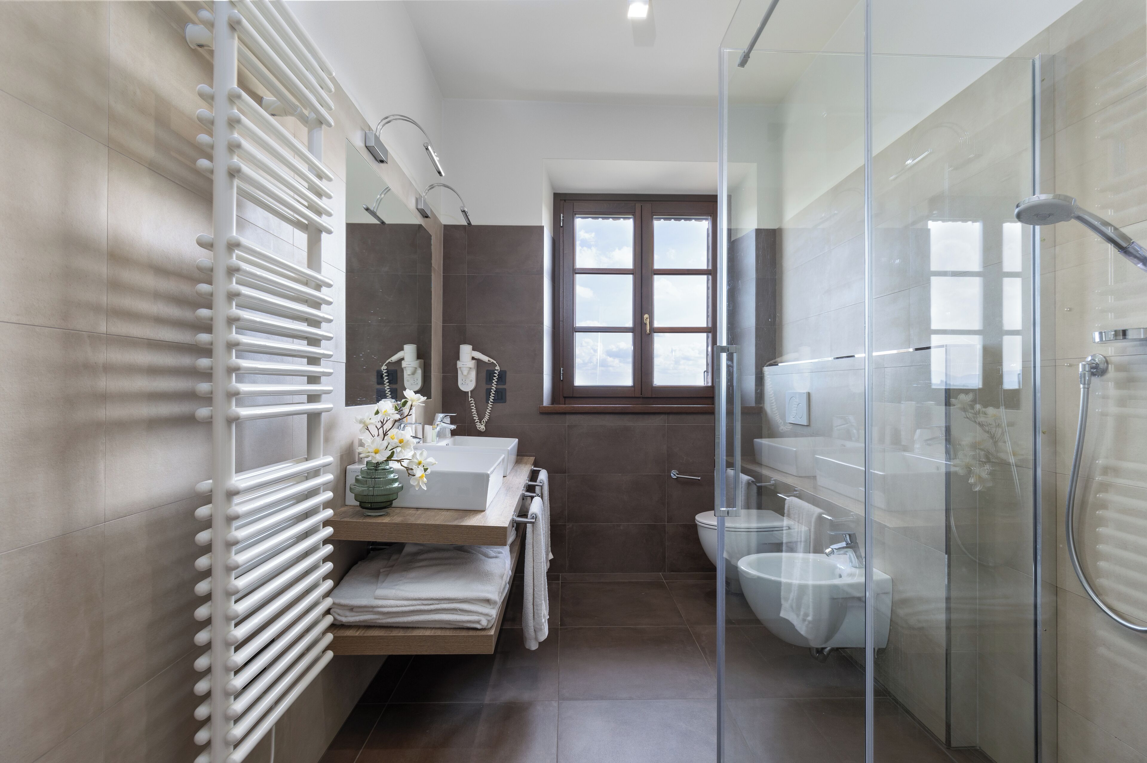 A modern bathroom with a glass shower enclosure, a built-in sink, and a towel rack.