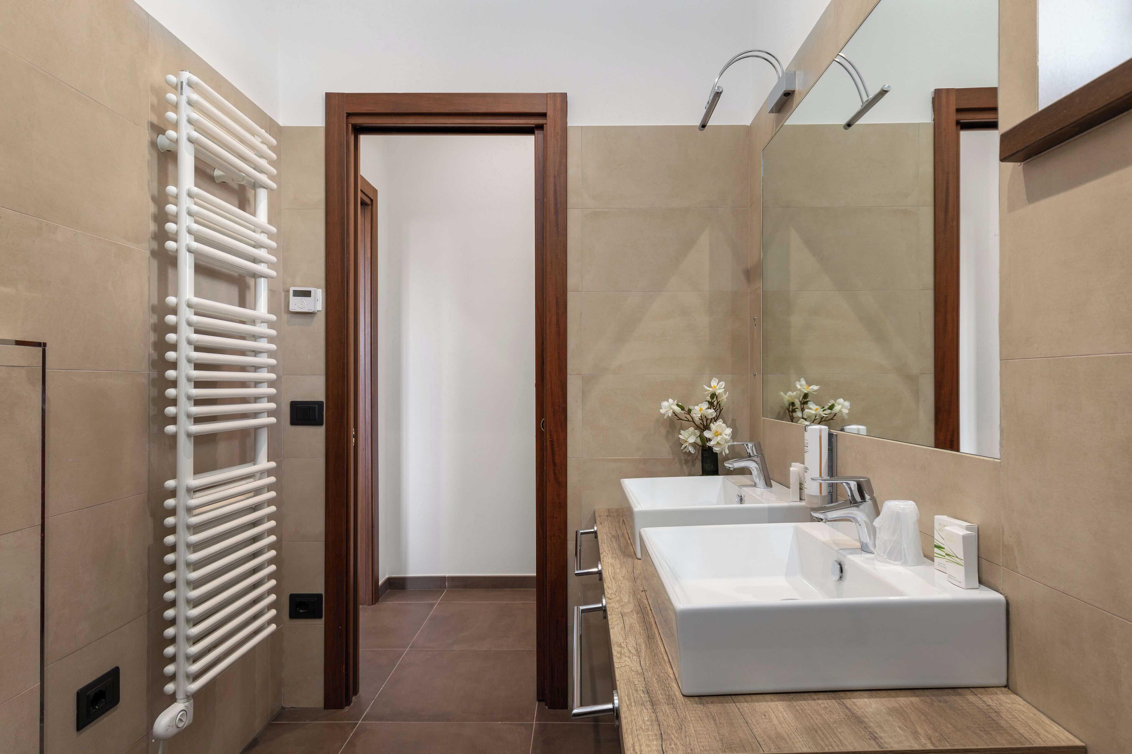 Een moderne badkamer met twee wasbakken, een grote spiegel en een handdoekrek.