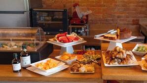 Buffet com diversas opções de comida, incluindo frutas, doces e acompanhamentos.