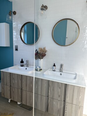 Two sinks with white countertops and cabinetry offer ample storage, complemented by large mirrors and a decorative vase.