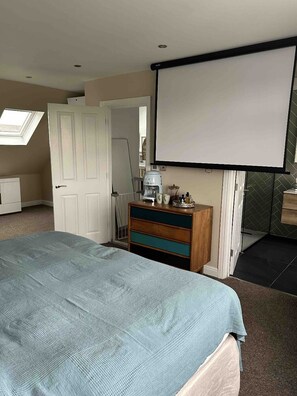 Relax in a spacious room with a large bed, a dresser, and a projector screen.