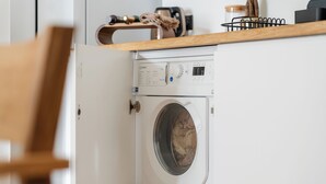 Una lavatrice a carica frontale in una cucina con un piano di lavoro in legno.