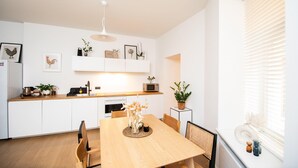Una cucina moderna con mobili bianchi, un tavolo da pranzo in legno e una lampada a sospensione.