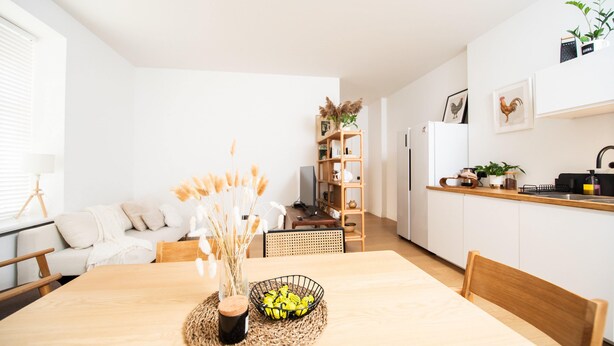 Una cucina moderna con mobili bianchi, un tavolo da pranzo in legno e un'isola della cucina.