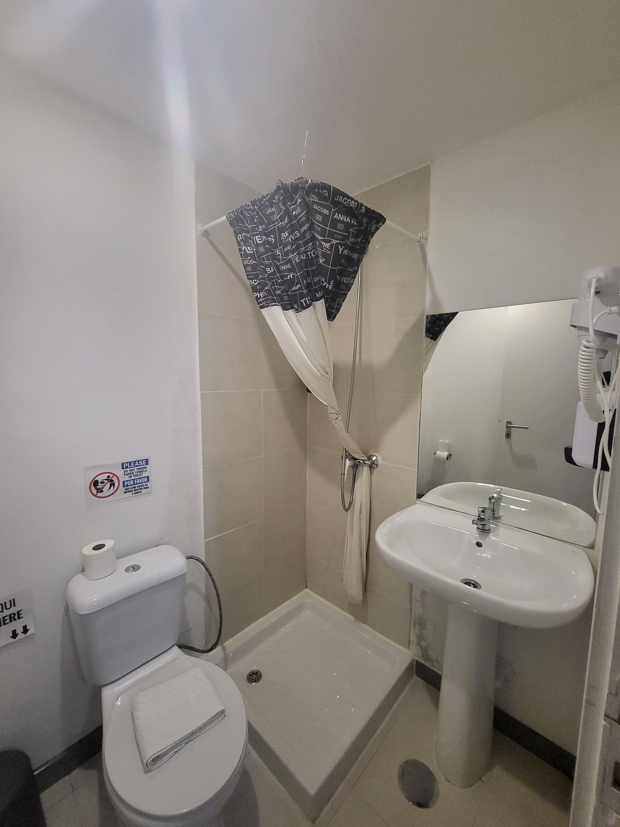Et lille badeværelse med toilet, håndvask og brusebad.
