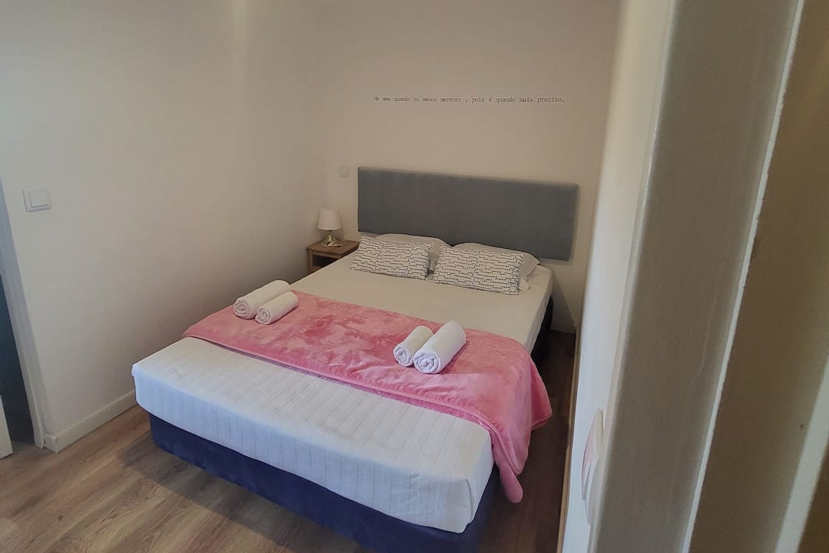 A bedroom with a bed, pillows, a nightstand, and a bedside lamp.