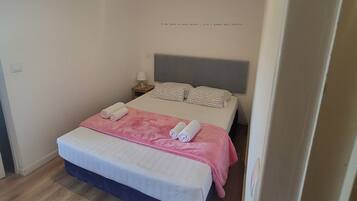 A bedroom with a bed, pillows, a nightstand, and a bedside lamp.