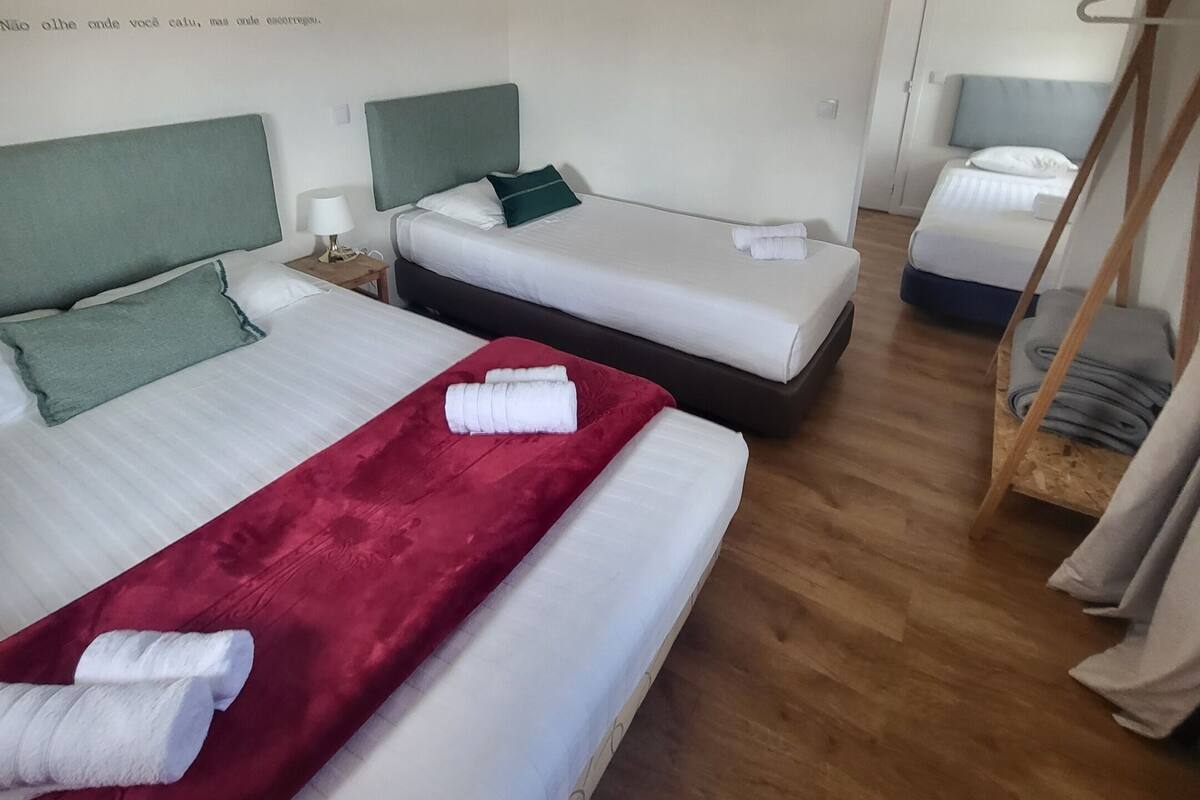 A hotel room with two beds, a red blanket, and a wooden floor.