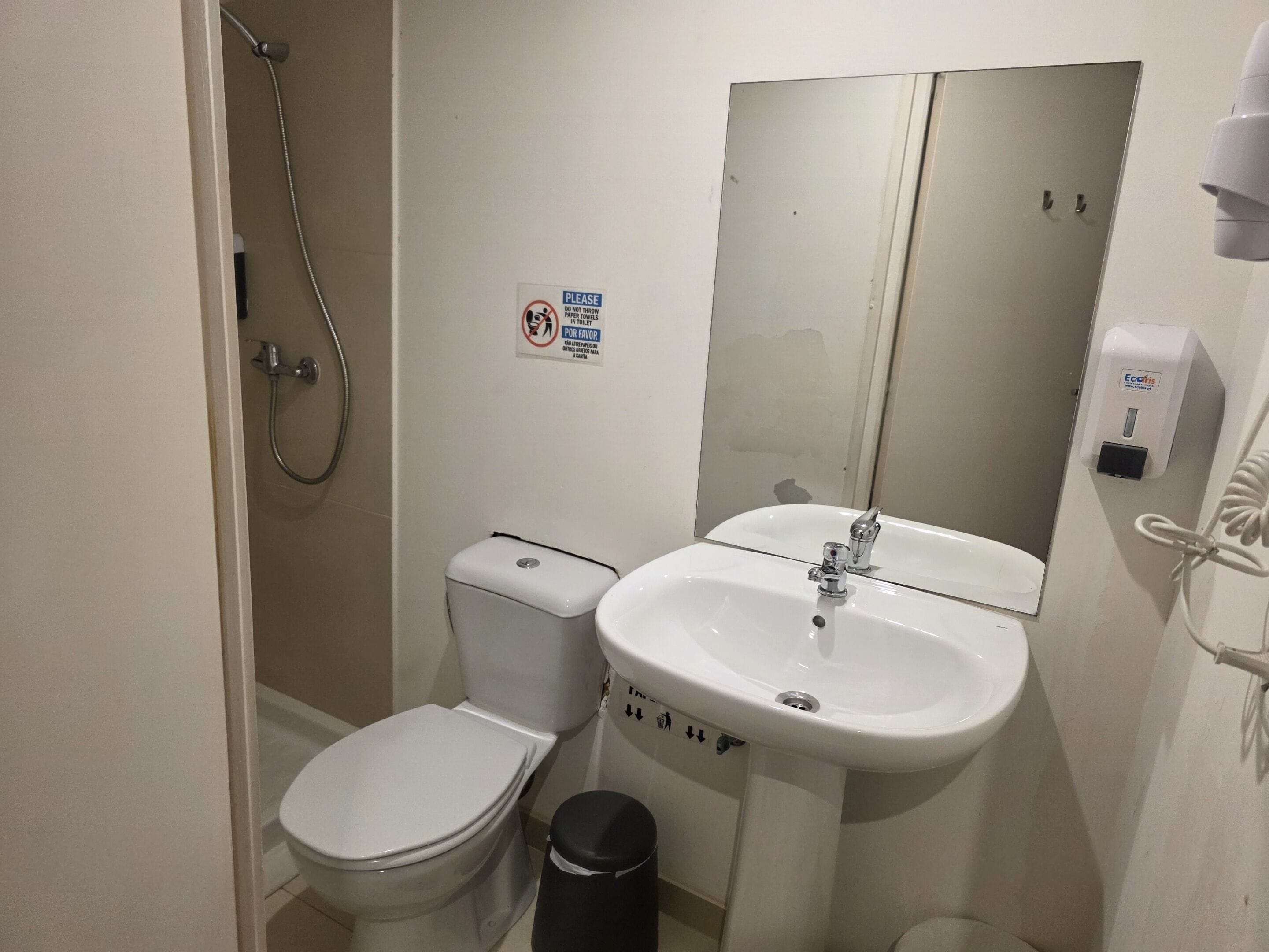 A small bathroom with a toilet, sink, and shower.