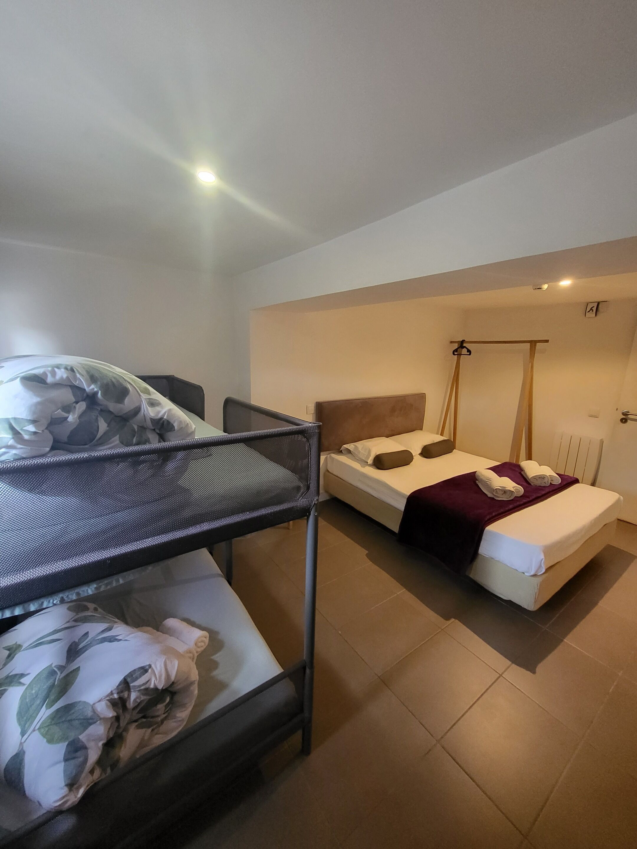 Une chambre avec un lit superposé, un lit simple et une chaise.