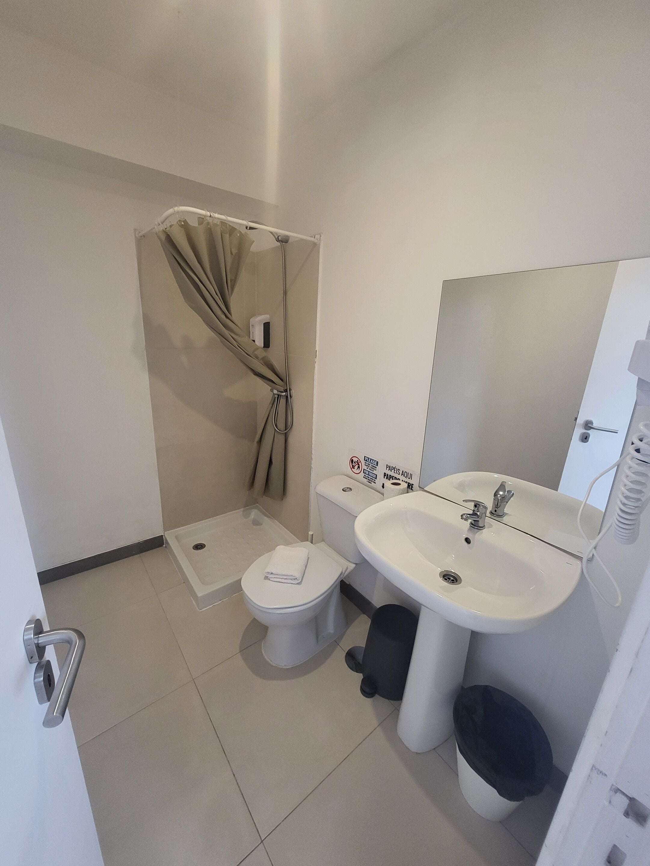 A compact bathroom with a shower, toilet, and sink.