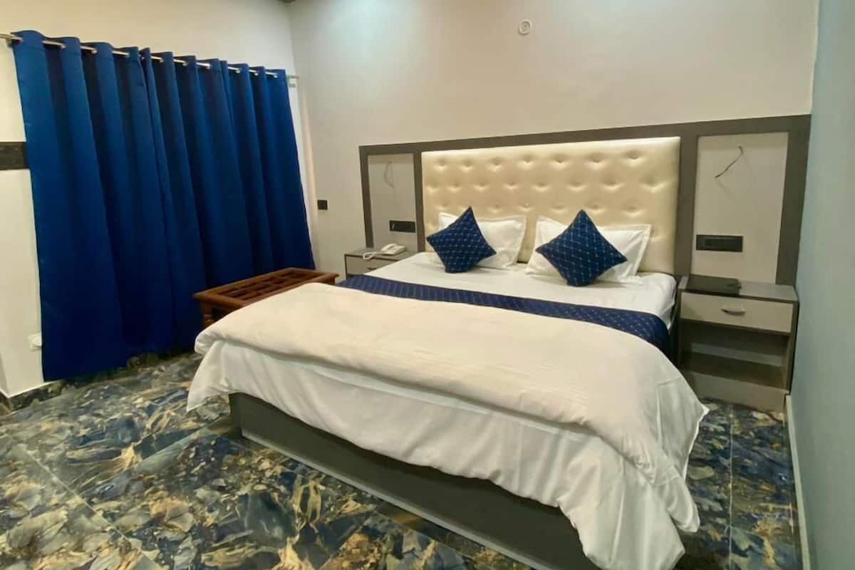 A modern bedroom with a large bed, a headboard with a tufted design, and a nightstand with a phone.