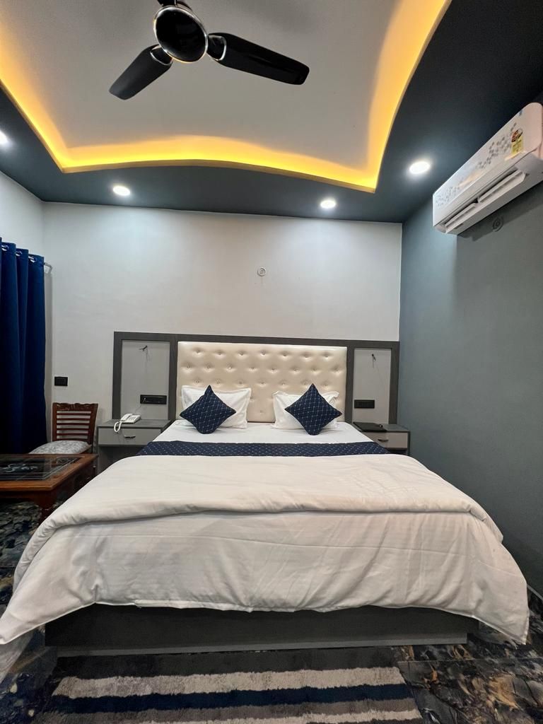 Una habitación de hotel con cama, mesitas de noche, ventilador de techo y aire acondicionado.