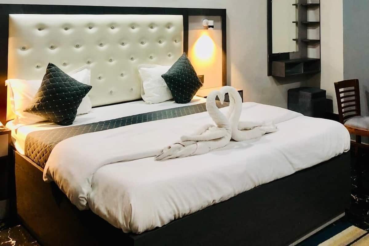 A modern hotel room with a tufted headboard, a large mirror, and a ceiling fan.