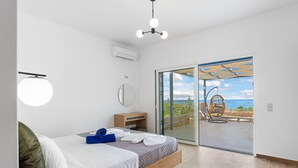Ein Schlafzimmer mit einem Bett, einem Nachttisch, einem Spiegel und Blick ins Freie durch eine Glastür.