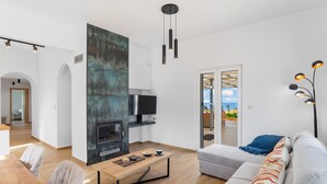 Ein modernes Wohnzimmer mit Kamin, Fernseher und einer Couch.