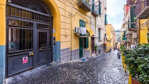 Una estrecha calle adoquinada con edificios amarillos, una verja negra y una señal de 'prohibido estacionar'.