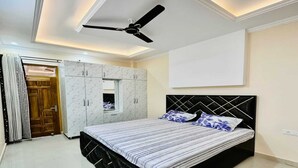A bedroom with a bed, wardrobe, ceiling fan, and a large window. - Urbanaid Uniworld (Bara Banki)