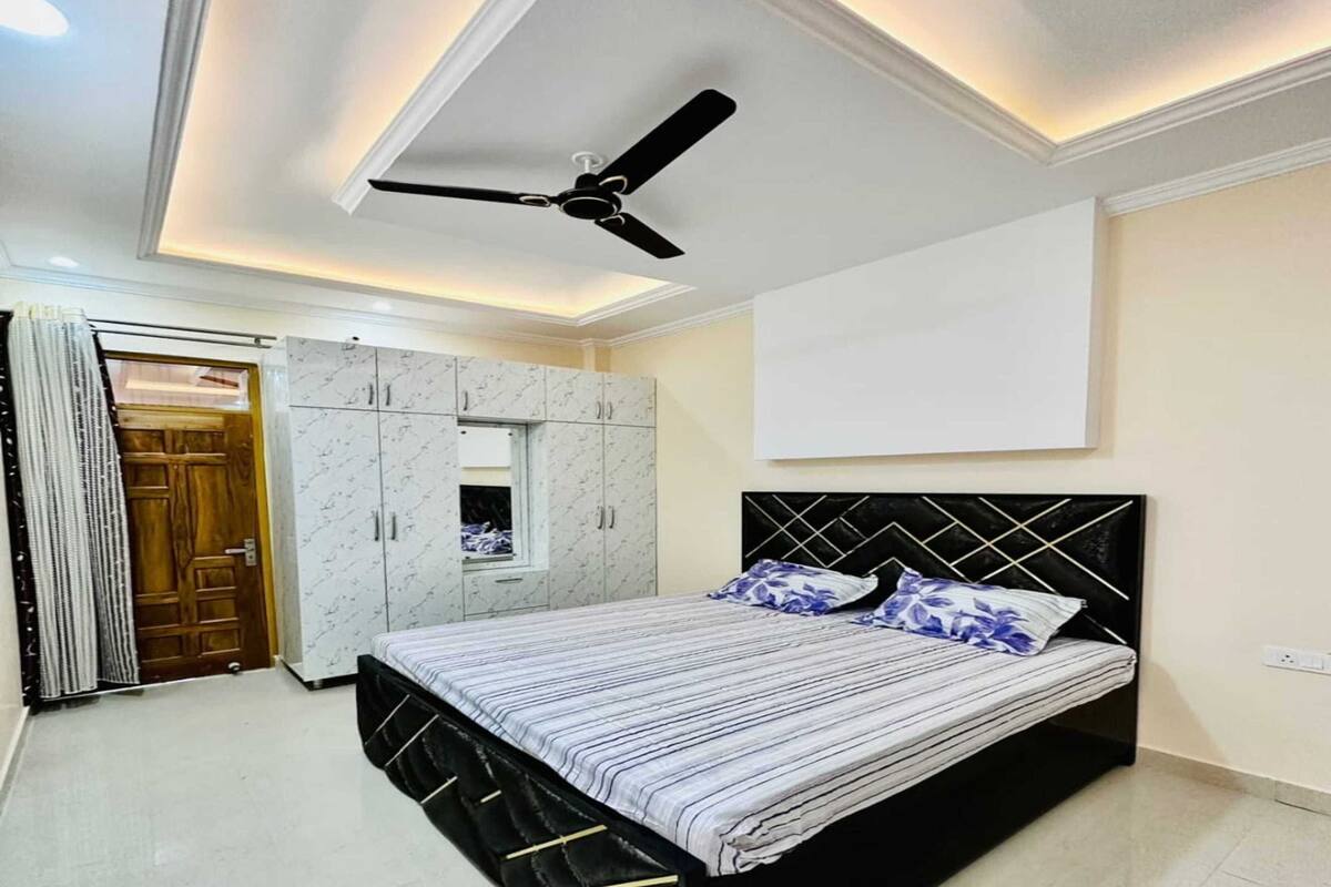 Une chambre à coucher comprenant un lit, une armoire, un ventilateur de plafond et une grande fenêtre.