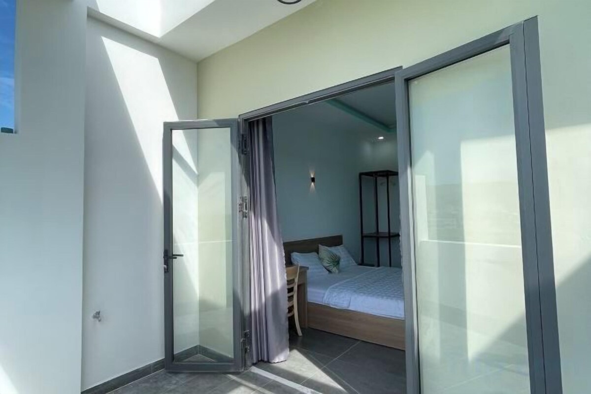 Een slaapkamer met een bed, een schuifdeur en uitzicht op de omgeving.