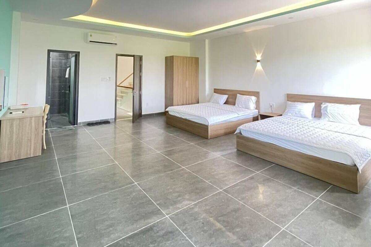 Un dormitorio moderno con dos camas, un escritorio y una zona de ducha.