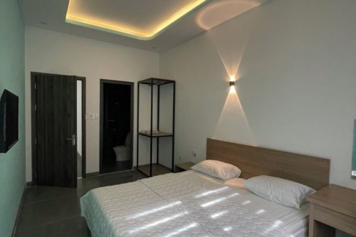 A modern bedroom with a bed, bedside table, and a wall-mounted light fixture.