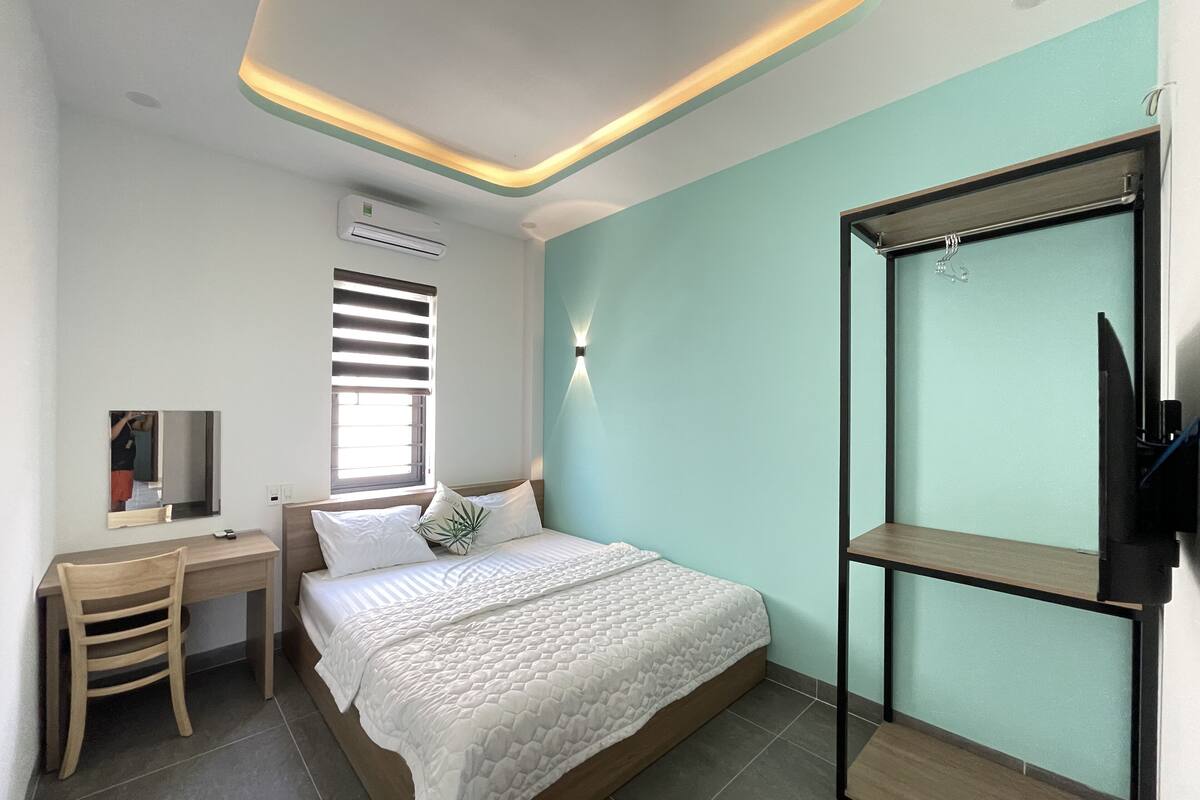 Un dormitorio moderno con cama, escritorio, silla, televisor y armario.