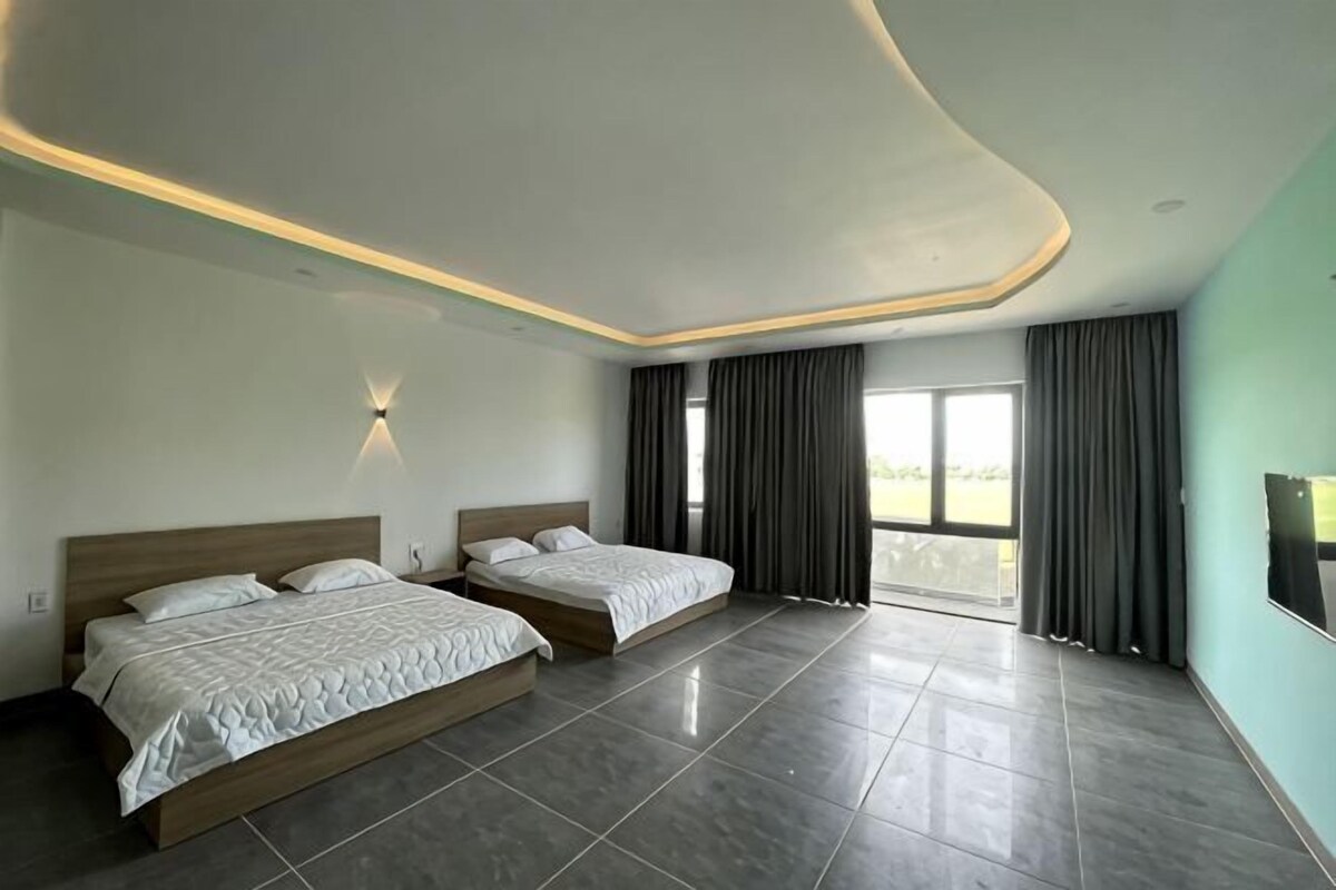 A hotel room with two beds, a large window, and a view of the outdoors.