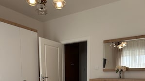A hotel room with a bed, a wardrobe, a mirror, and a door. - Coastal Comfort Apartment (Podstrana)