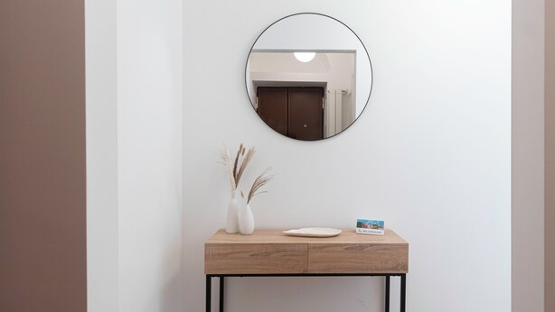 A minimalist console table with a round mirror, a white vase with dried plants, and a "No Smoking" sign. - Italianway Comfort - Confalonieri 11 (Milan)