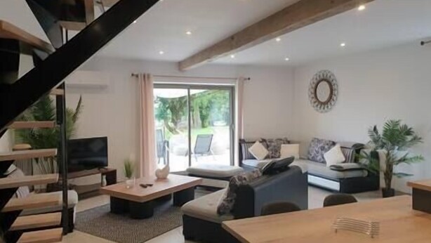 En moderne stue med trappe, sofaarrangement, sofabord og spisebord.