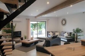 Ein modernes Wohnzimmer mit Treppe, einer Sofagarnitur, einem Couchtisch und einem Esstisch.
