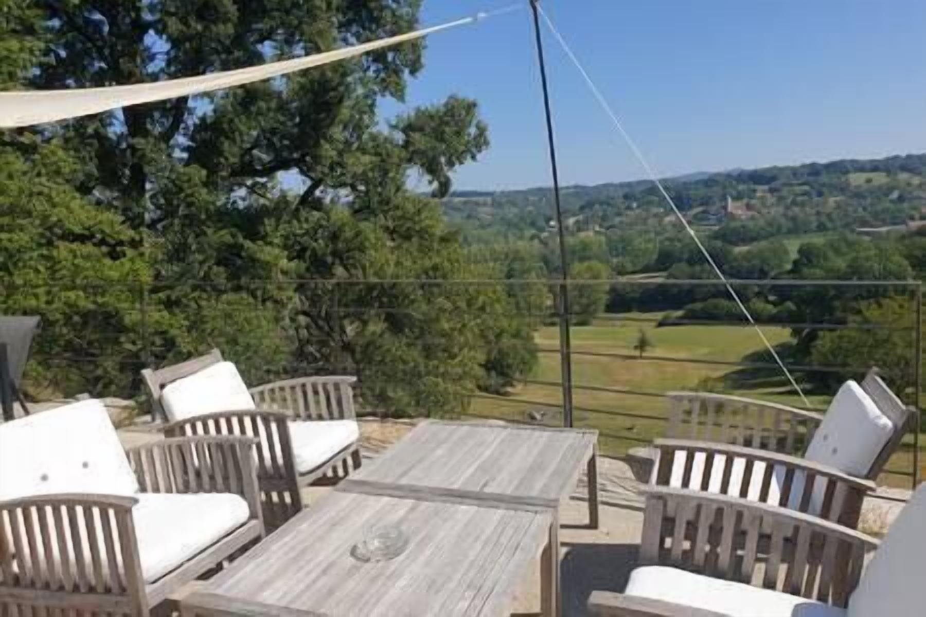 En terrasse med træmøbler og udsigt over et grønt landskab.