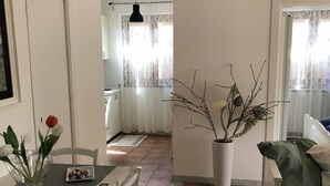 Un coin repas comprenant une table, des chaises, un vase avec des fleurs et une vue sur la cuisine.
