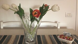 Une photographie encadrée représentant une route de montagne avec un véhicule, un vase de tulipes et un panier de chocolats posés sur une table.