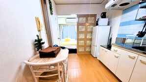 A compact kitchen with a small dining table and chairs, a refrigerator, and a sink. - Grand Colbert NANBA 505, 605, 704 (Osaka)