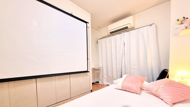 A bedroom with a bed, a projector screen, an air conditioning unit, and a curtain. - Grand Colbert NANBA 505, 605, 704 (Osaka)