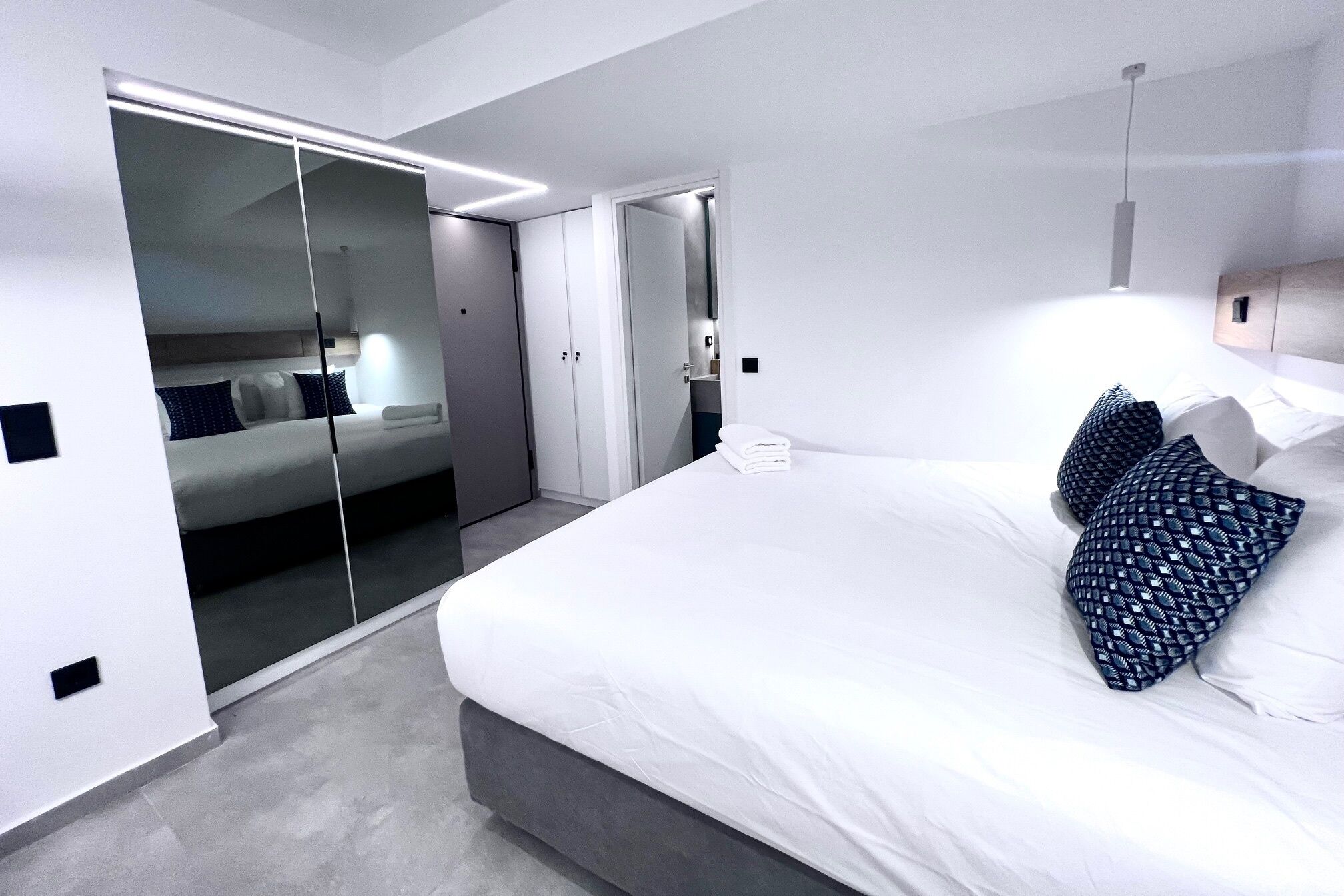 Une chambre d’hôtel moderne dotée d’un grand lit, d’un dressing et d’une salle de bain séparée.