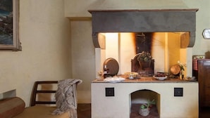 A cozy room with a fireplace, a bench, and a table with various items. - Apartment in historic villa with swimming pool near Florence (Sesto Fiorentino)