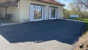 Une maison avec un toit en tuiles, un patio couvert avec des meubles d’extérieur et une grande allée.