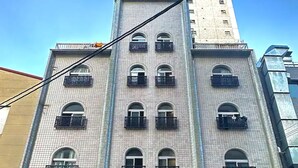Un immeuble à plusieurs étages, doté d’une façade carrelée, de nombreux balcons et de climatiseurs.