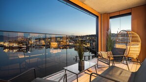 A balcony with a glass railing overlooking a cityscape at dusk. - TotalApartments Vervet Fram F (Tromsø)