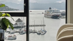 A room with a large window overlooking a harbor with boats and a cruise ship. - TotalApartments Vervet Fram F (Tromsø)