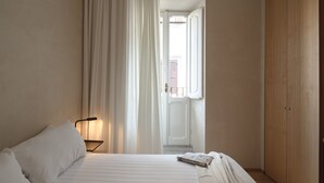 Un dormitorio con una cama, una mesita de noche, una lámpara, una puerta y un armario.