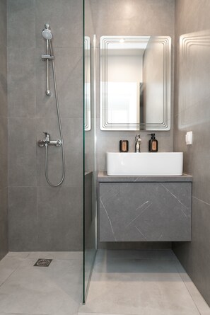 Superior appartement | Badkamer | Een douche, een regendouche, een haardroger, handdoeken