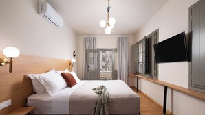Quarto com cama, mesa de cabeceira, luminária, ar condicionado e TV na parede.
