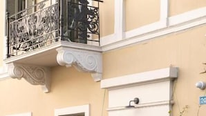 A building with a balcony, a door with a sign, and a sign with "LY" and "ACROPOLIS".